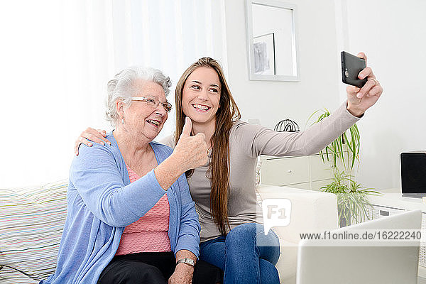 old senior woman making a selfie with her young granddaughter at home