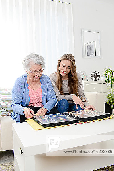 ältere Frau mit ihrer kleinen Enkelin zu Hause beim Betrachten von Erinnerungen im Familienalbum