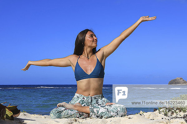 Junge Frau beim Yoga am Strand
