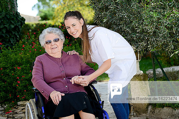 Ältere ältere Frau im Rollstuhl mit einer Krankenschwester im Freien in Pflegeheim Krankenhaus Garten.