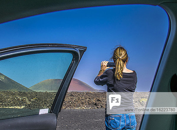 Spanien  Kanarische Inseln  Insel Lanzarote  Tourist beim Fotografieren des Vulkangebietes