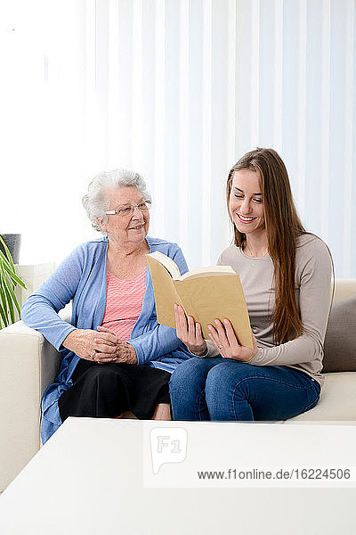 Fröhliche junge Frau hilft einer älteren Frau zu Hause mit dem Laptop