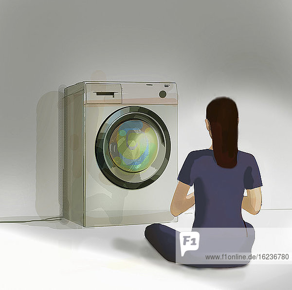 Frau meditiert vor der Waschmaschine