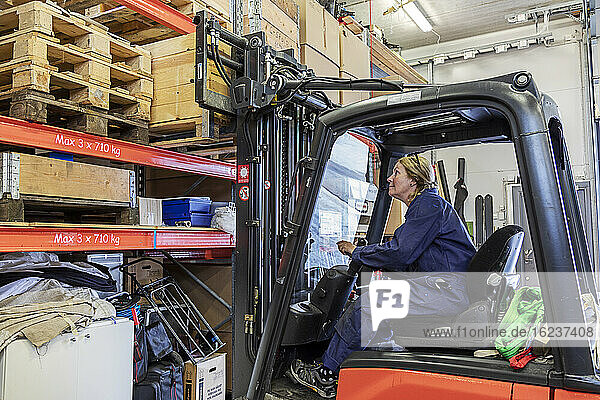Woman driving forklift truck in warehouse