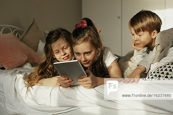 Children on bed using digital tablet