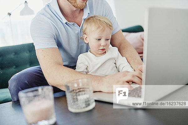 Vater und kleiner Sohn benutzen Laptop