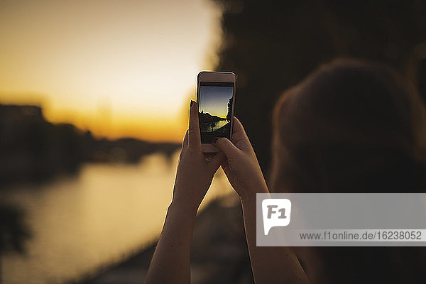 Woman taking picture of city at sunset