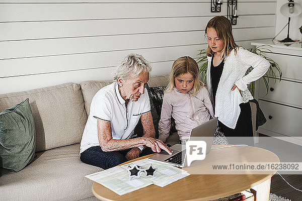 Grandmother with granddaughters using laptop
