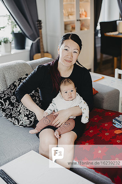 Frau sitzt mit Baby auf dem Sofa