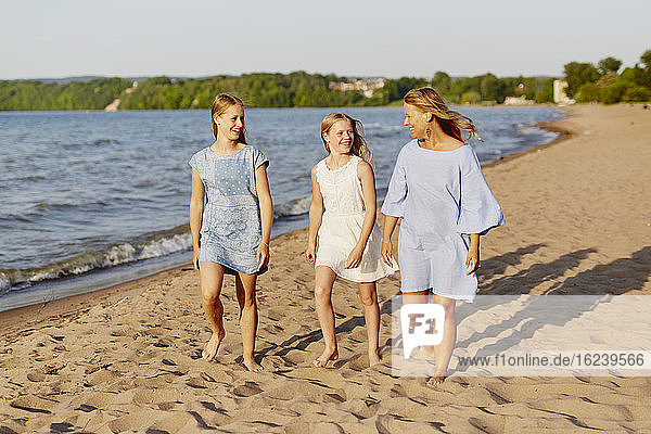 Mutter mit Töchtern spazieren am Strand