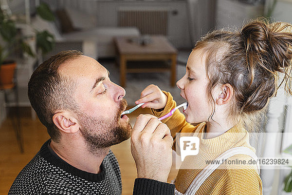 Vater und Tochter putzen sich gegenseitig die Zähne