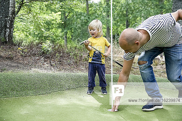 Father and son playing mini golf