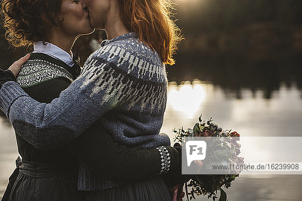 Lesbisches Paar küsst sich am Seeufer