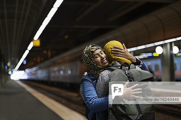 Female friends hugging on train station platform