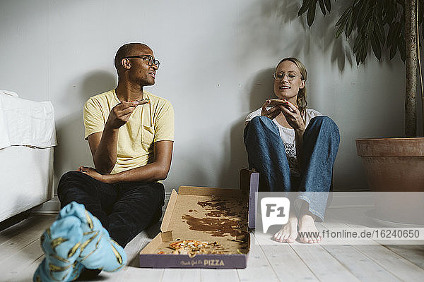 Couple sitting on floor and having pizza