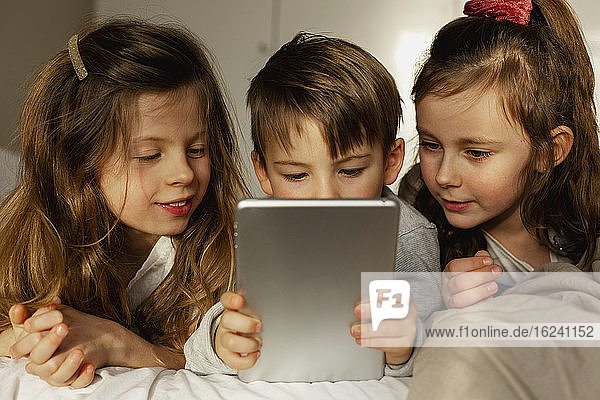 Kinder im Bett mit digitalem Tablet