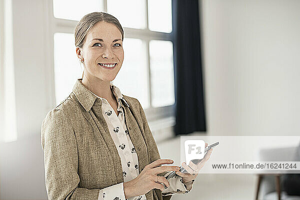 Businesswoman with cell phone looking at camera