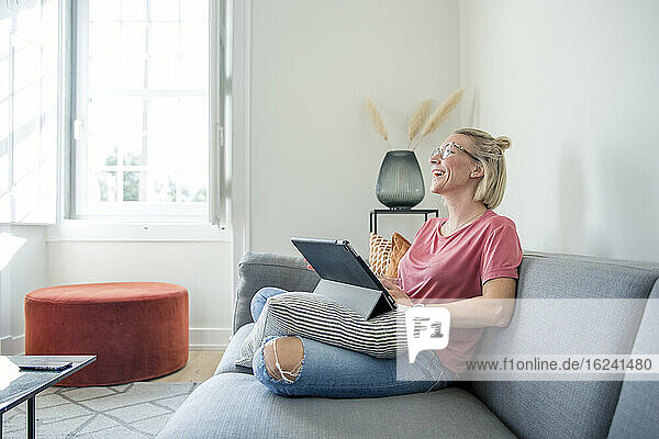Frau auf Sofa mit digitalem Tablet