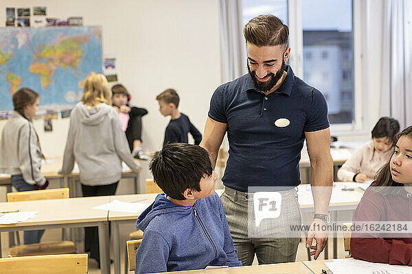 Teacher with schoolboy in classroom