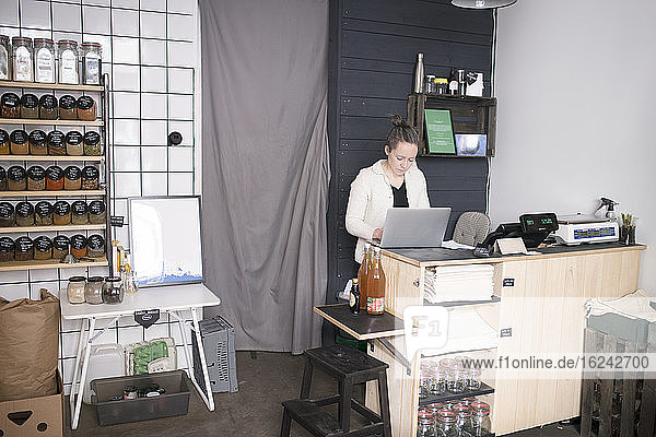 Woman using laptop in shop