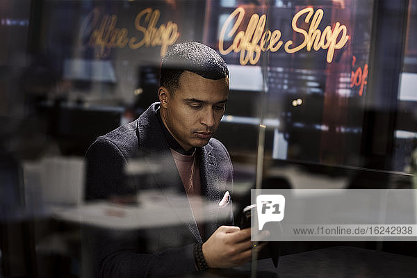 Mann benutzt Mobiltelefon in einem Cafe