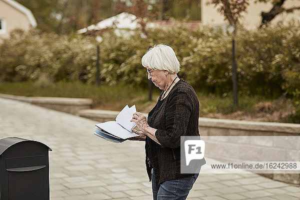 Ältere Frau steht in der Nähe des Briefkastens