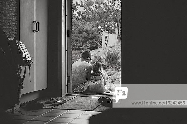 Vater und Tochter sitzen vor der Tür