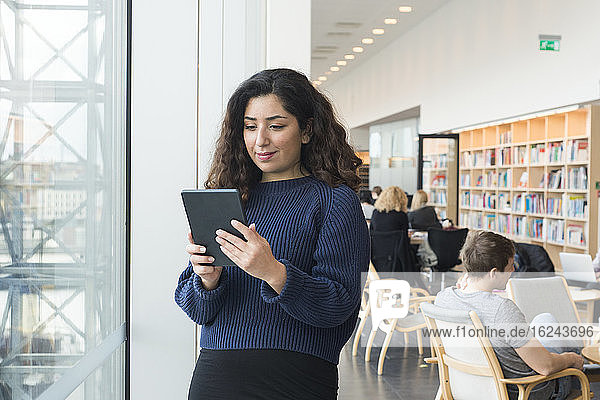 Frau benutzt digitales Tablet in der Bibliothek