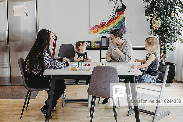 Eltern mit Töchtern sitzen am Tisch
