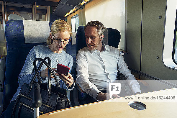 Man and woman in train looking at cell phone