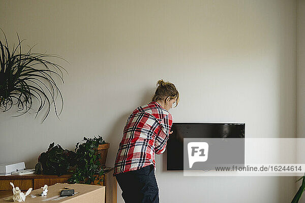 Frau hängt TV an die Wand