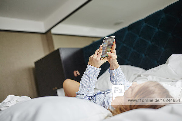 Frau benutzt Mobiltelefon im Bett