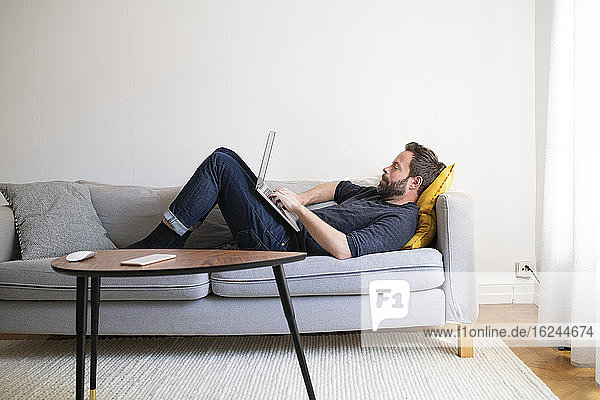 Mann auf Sofa mit Laptop