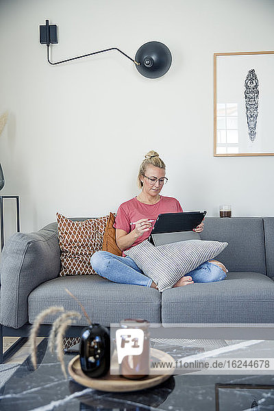 Woman on sofa using digital tablet