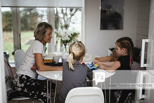 Grandmother playing board game with granddaughters