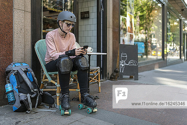 Weibliche Skaterin in einem Straßencafé