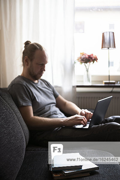 Mann mit Laptop auf dem Sofa