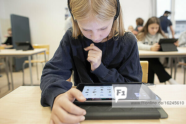 Girl in classroom using digital tablet