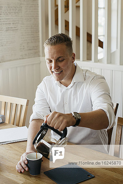 Mann gießt Kaffee aus einer Kaffeekanne ein