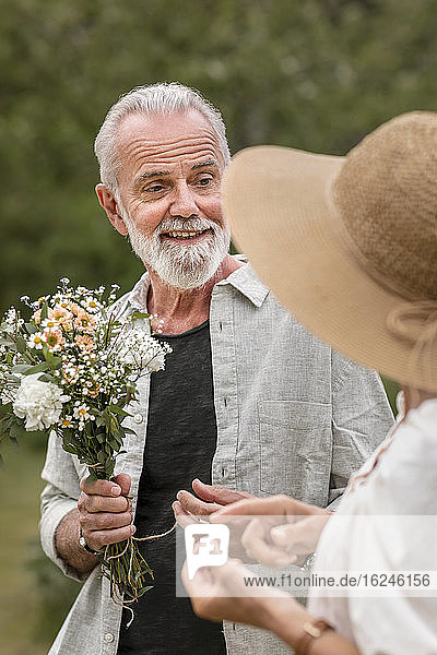 Älterer Mann hält Blumenstrauß