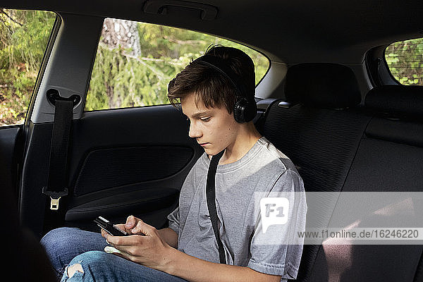 Junge benutzt Mobiltelefon im Auto