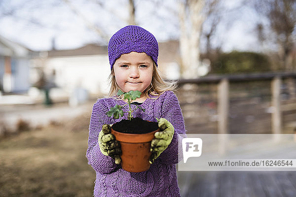 Girl holding pot with plant