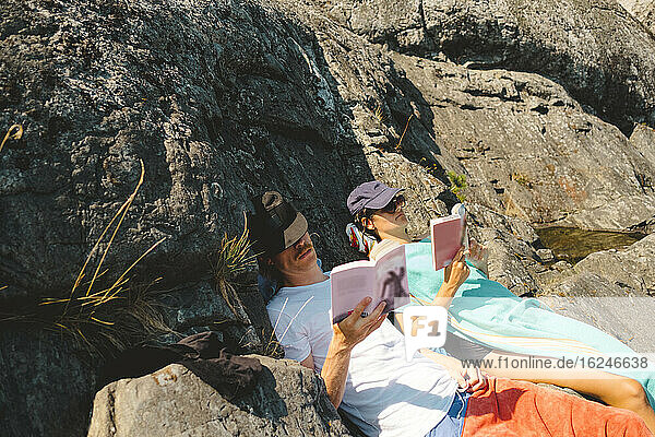 Mann und Frau lesen Bücher auf Felsen