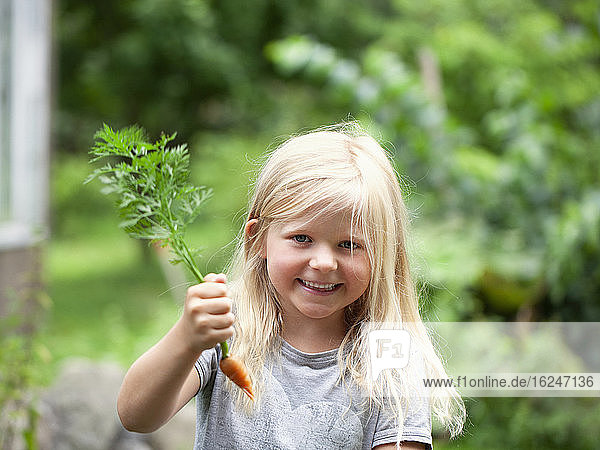 Lächelndes Mädchen hält Karotte