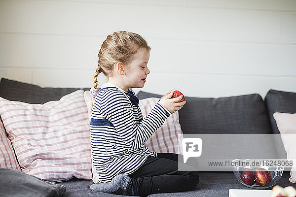 Mädchen auf Sofa isst Apfel