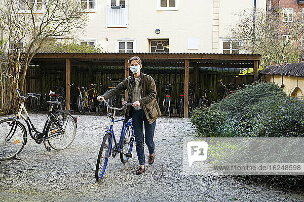 Frau mit Fahrrad und Gesichtsmaske