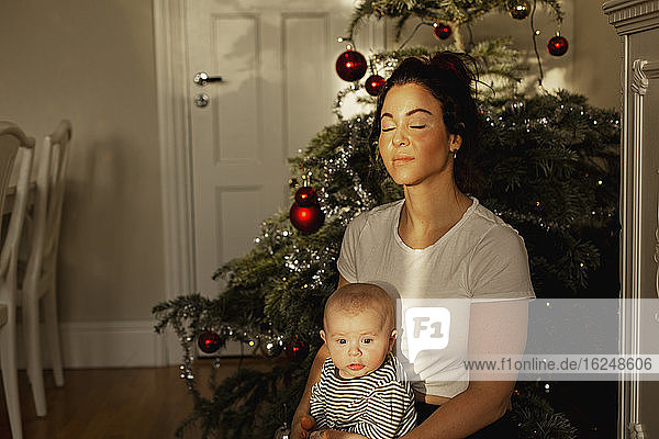 Mother with baby in front of Christmas tree