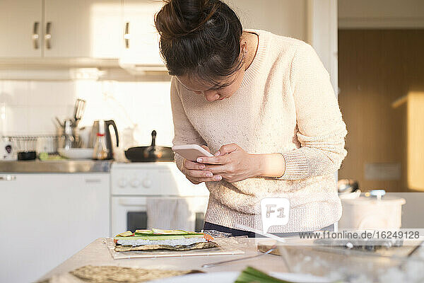 Woman photographing food in kitchen