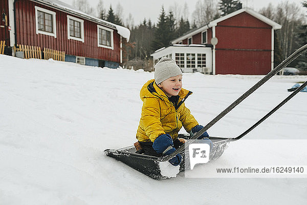 Boy on sleigh snow shovel