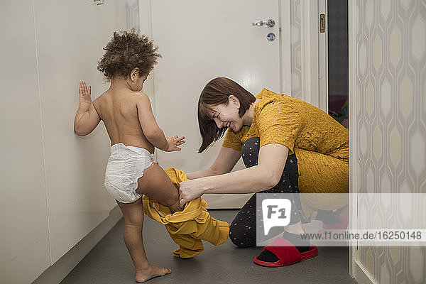 Mother helping daughter to get dressed